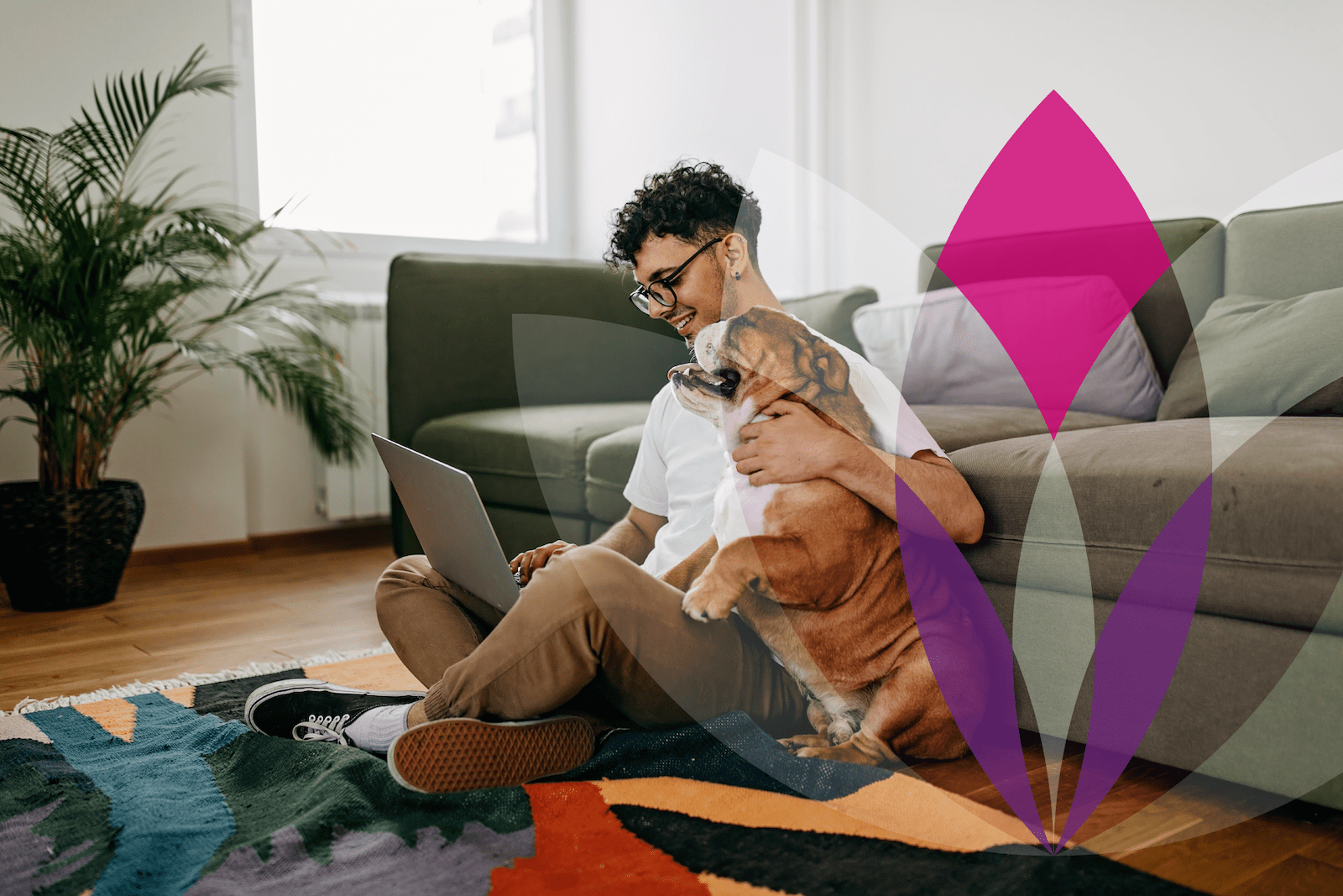 Young man sitting on floor with laptop and bulldog on lap